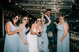 Bride and bridal party in white love heart sunglasses doing a champagne spray at Silverwood lodges, errol, perthshire at night with flash