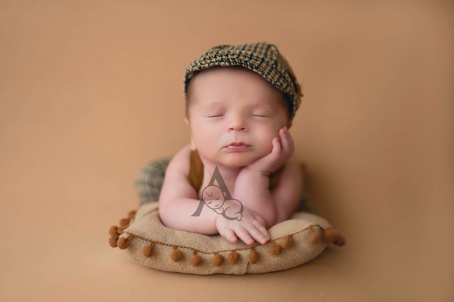 Sleeping newborn posed in basket wearing knit cap on warm brown backdrop during professional portrait session.