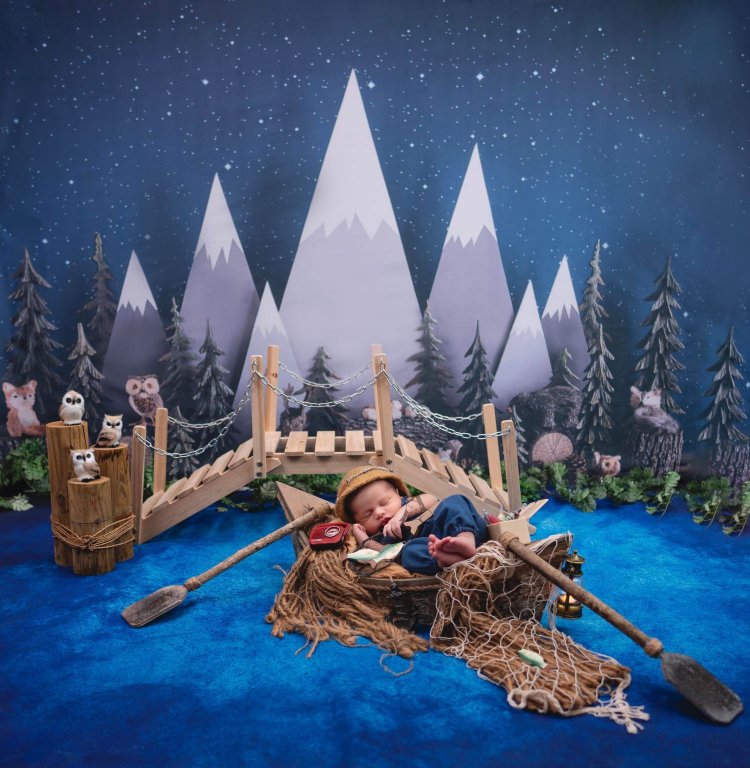 Whimsical winter scene with toy boats on blue water against snowy mountains and starry night sky backdrop.