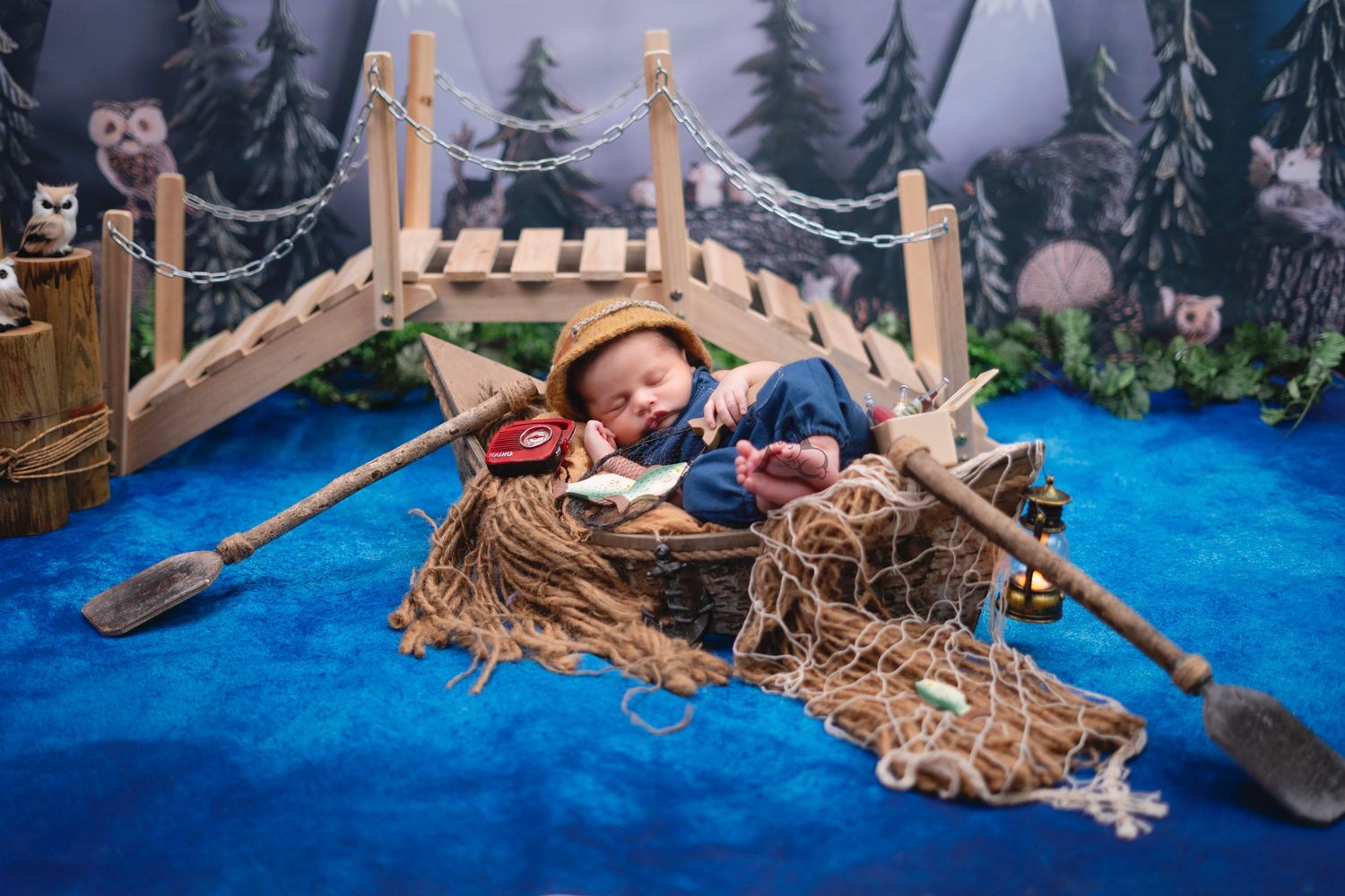 Close-up of miniature wooden boats and fishing nets against a winter forest backdrop.