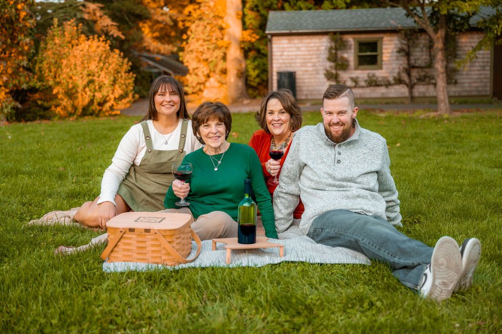 A group enjoys a picnic on a blanket in front of a house during golden hour.