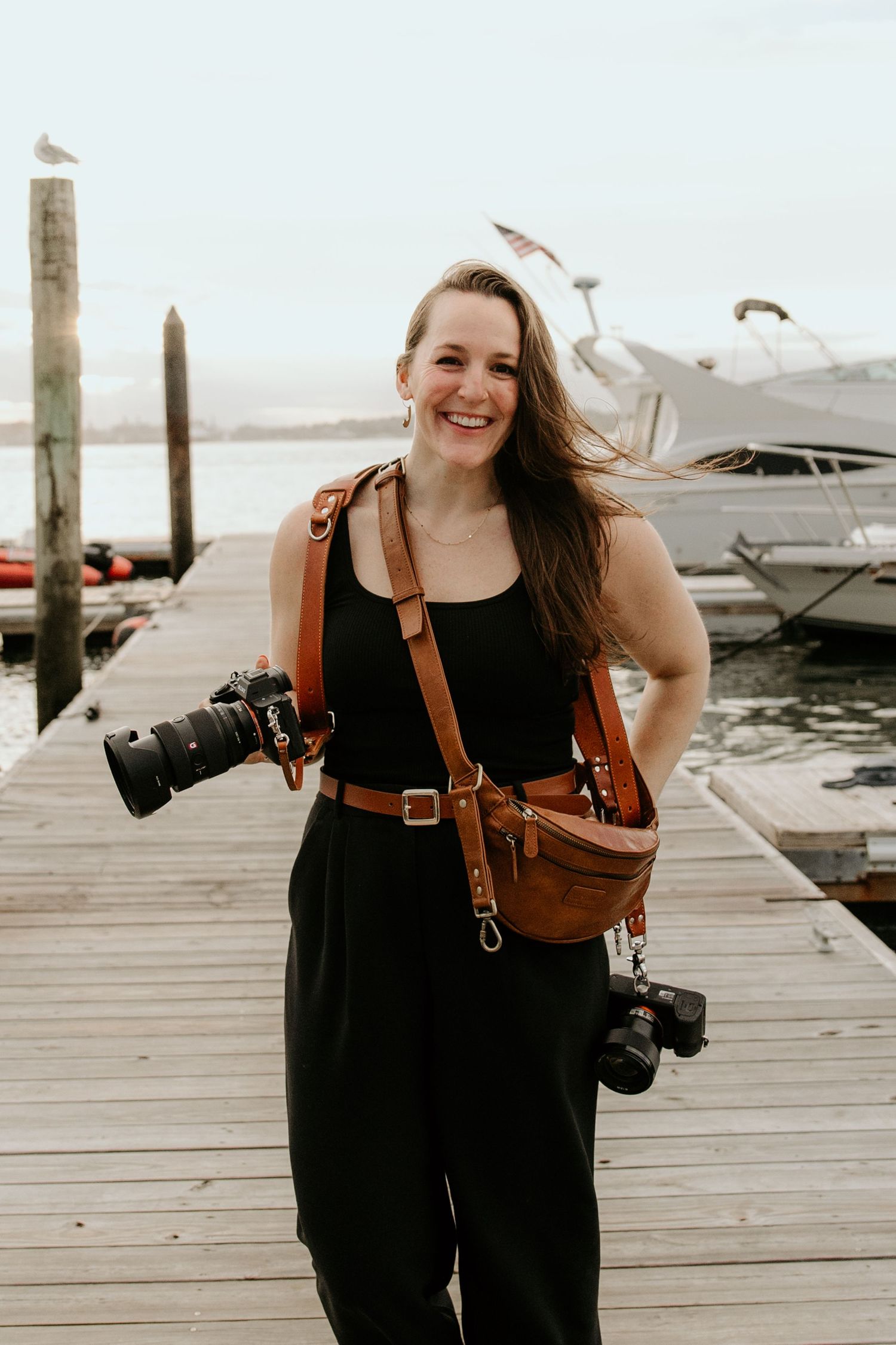Professional photographer with cameras on wooden dock by marina.