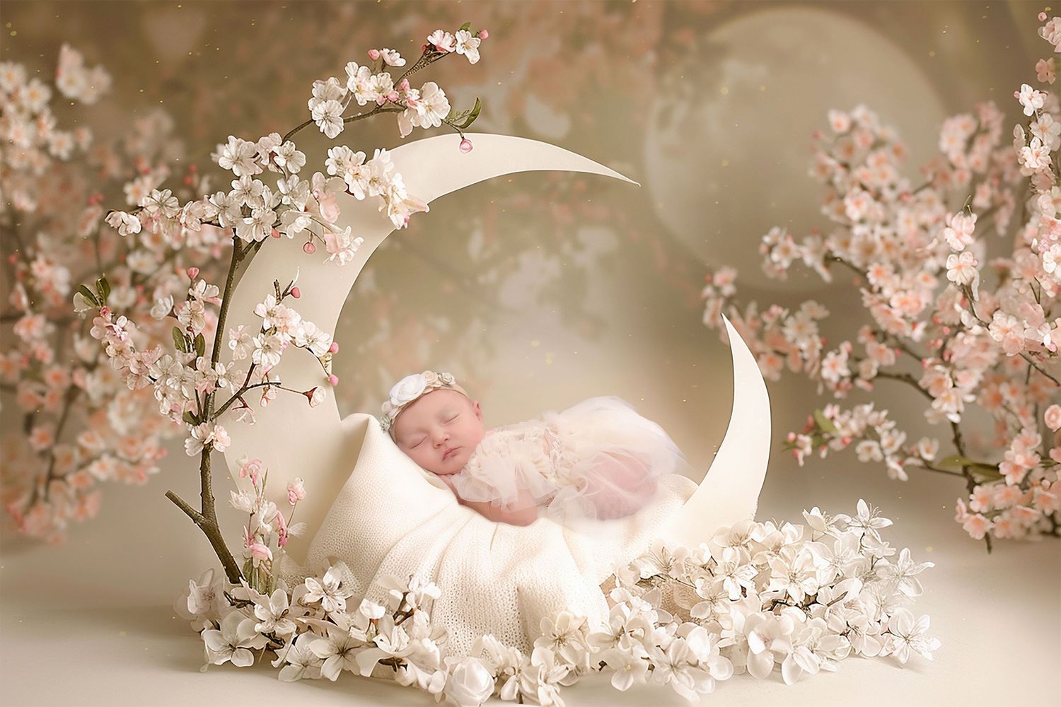 Sleeping newborn posed on crescent moon prop with pink cherry blossoms.