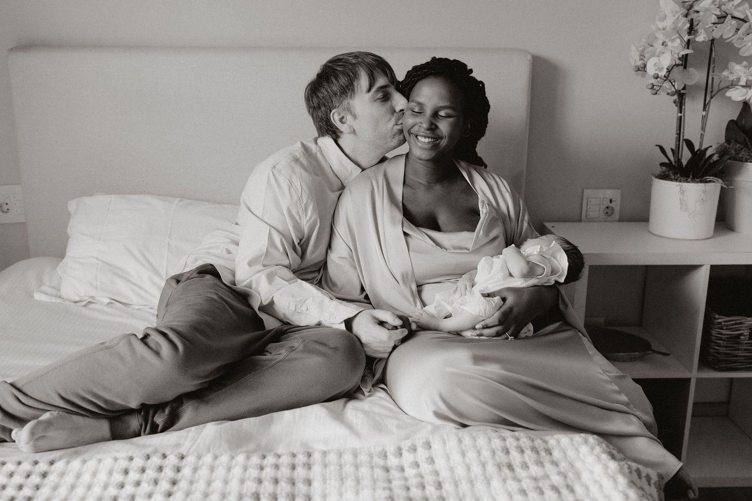 Natural light photograph capturing tender family moment on textured white bedding.