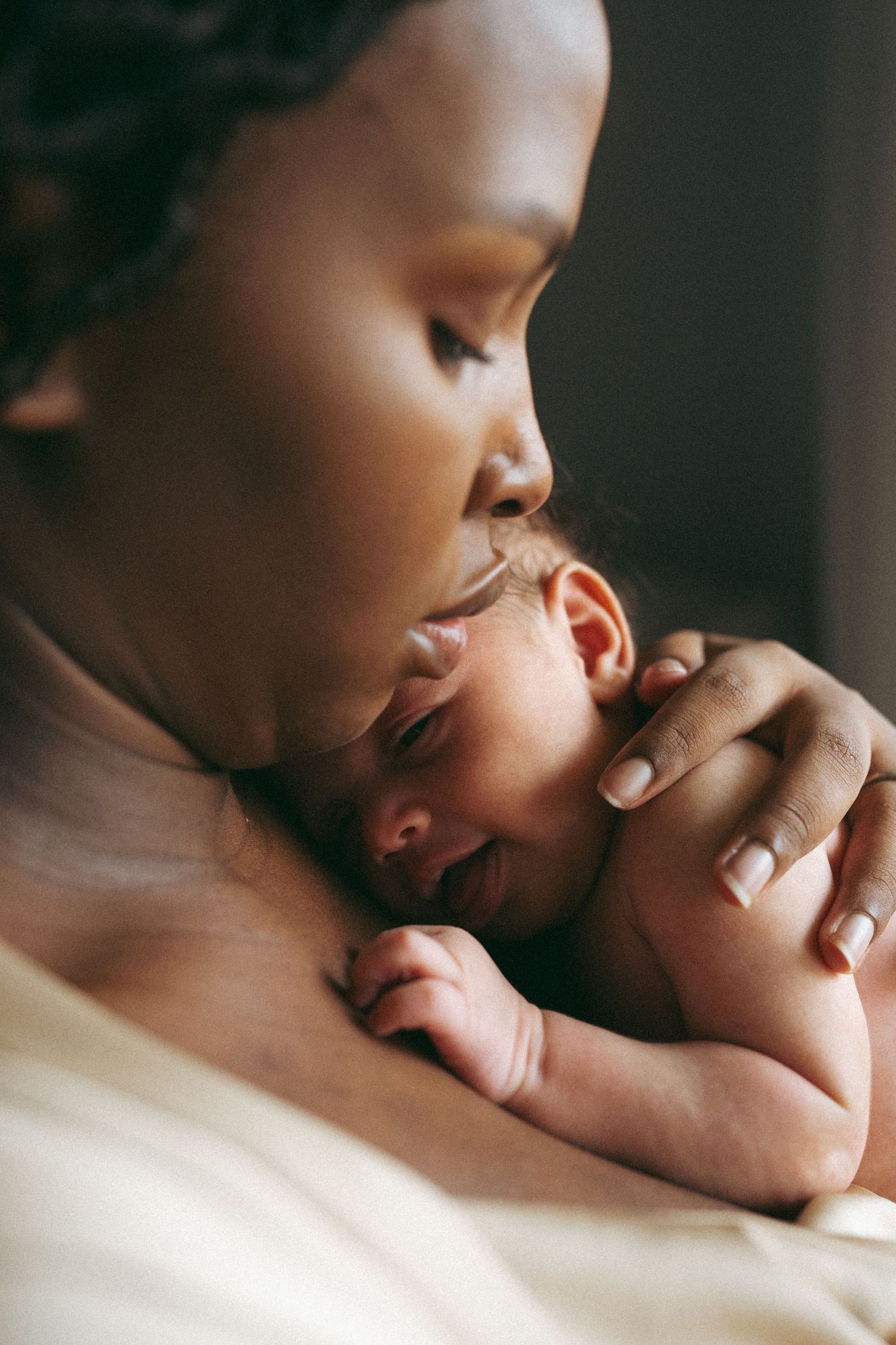 Intimate close-up of a tender moment between parent and newborn baby in soft natural lighting.