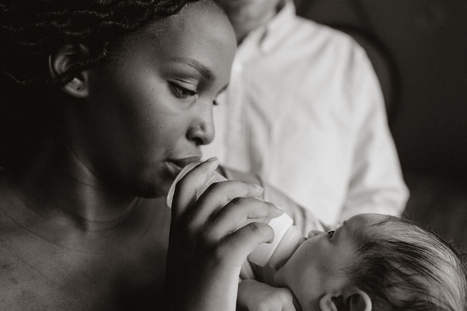 Black and white photograph capturing an intimate bonding moment with a newborn.
