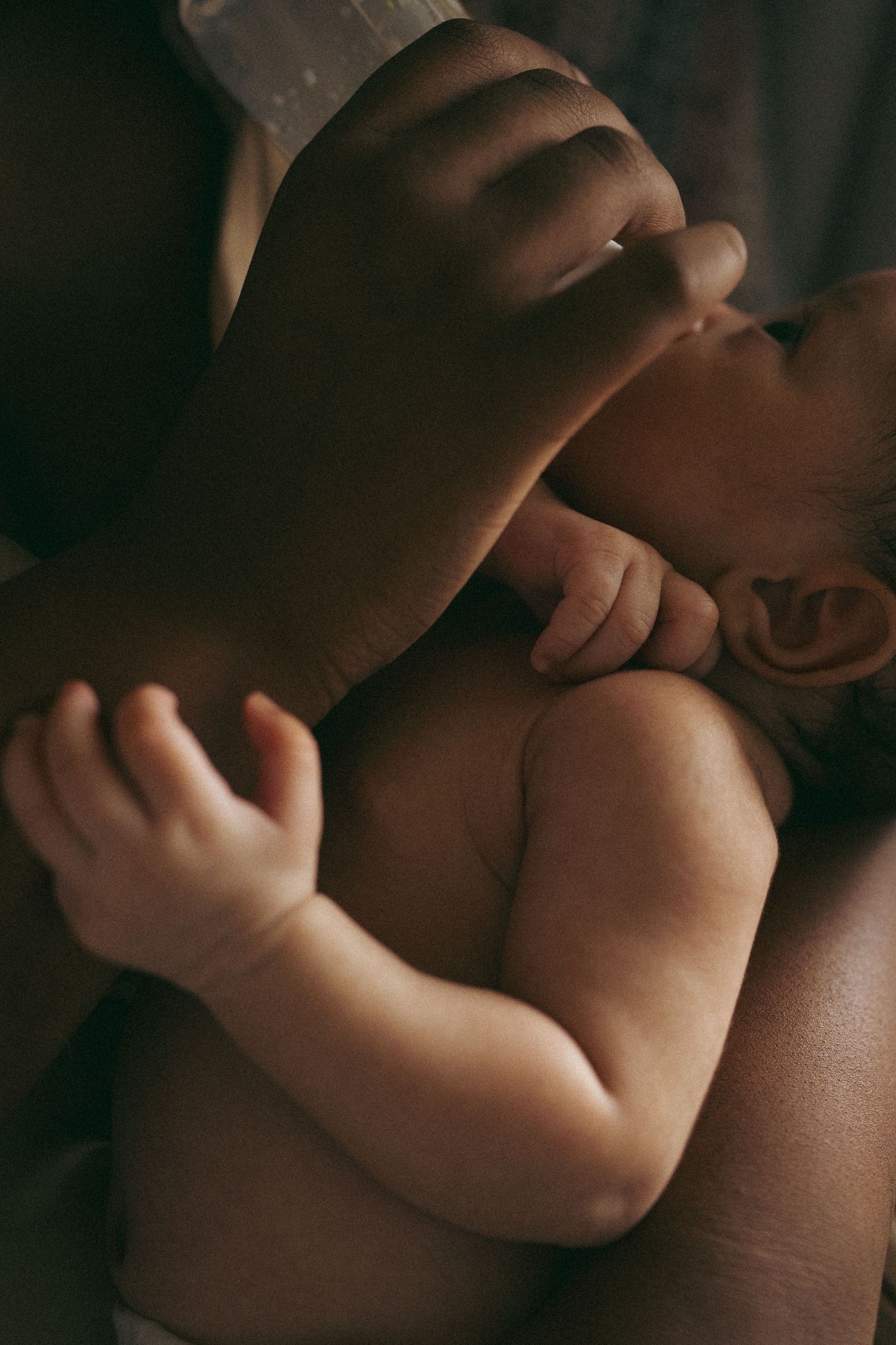 Close-up shot of tiny baby hands reaching out during a tender embrace.