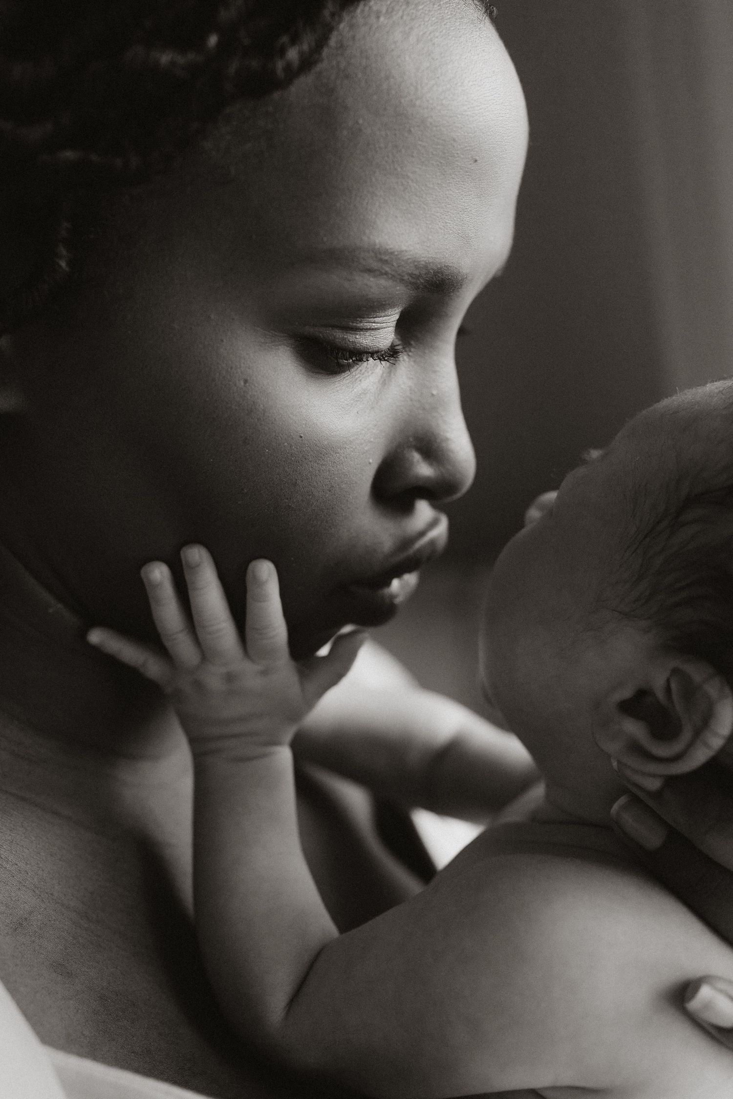 Black and white close-up of tender moment between parent and baby.