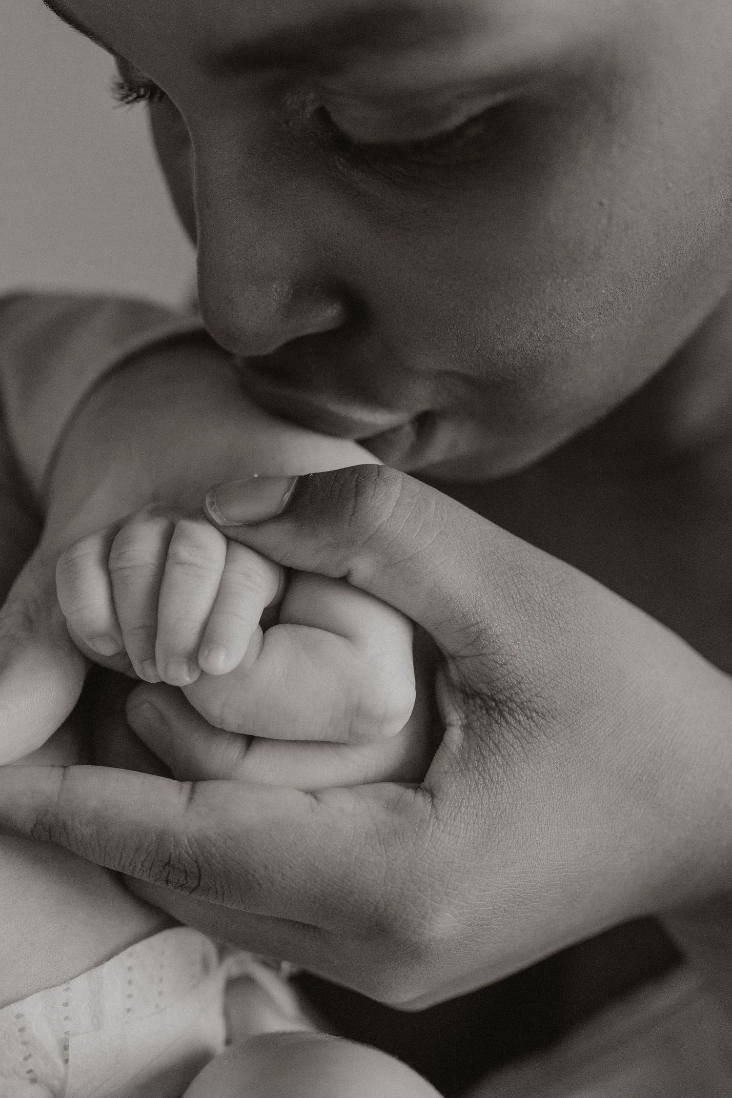 Black and white close-up series showing gentle kisses on tiny baby fingers.