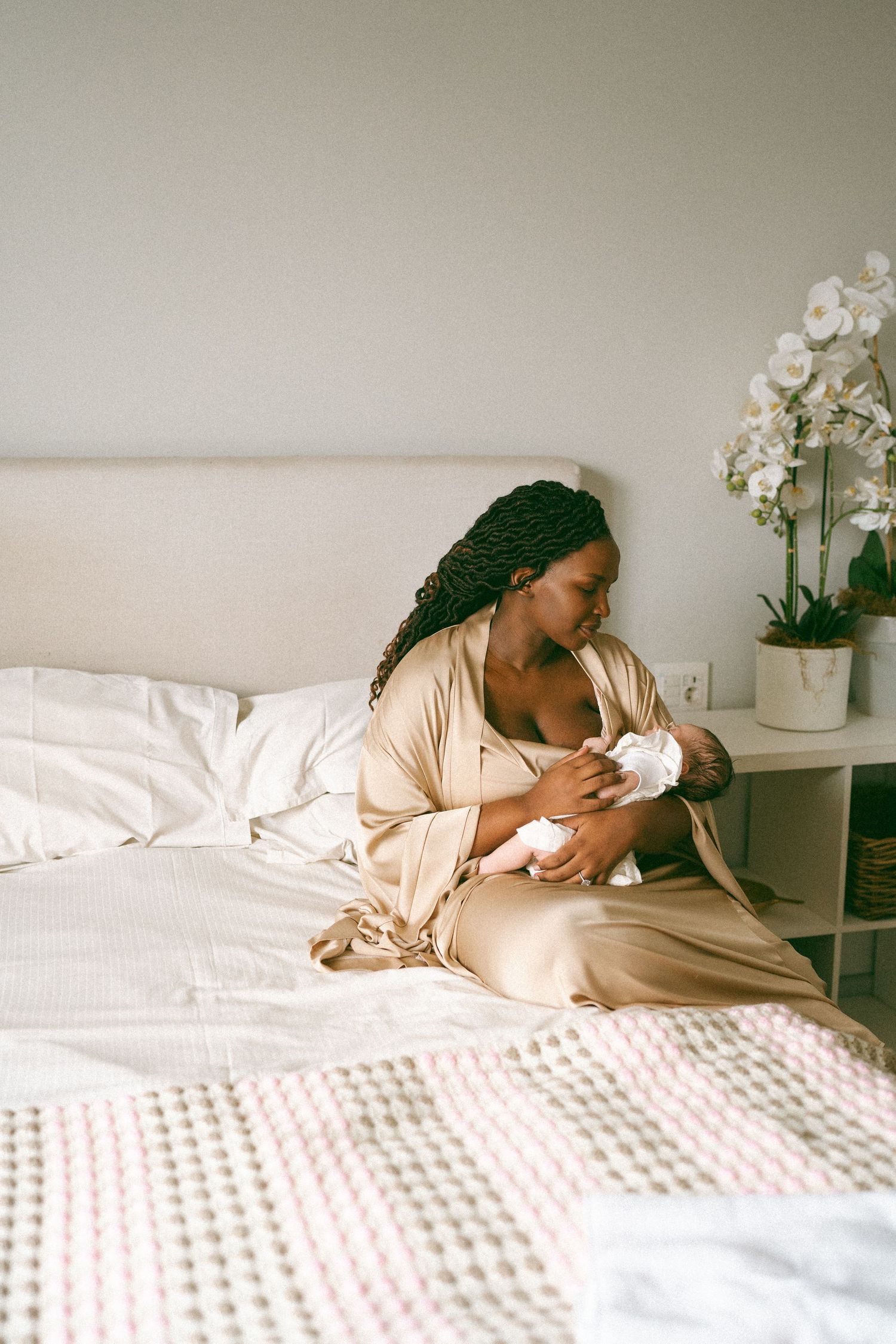 Intimate black and white photograph showing tender moments of bonding with a newborn on a white bed.