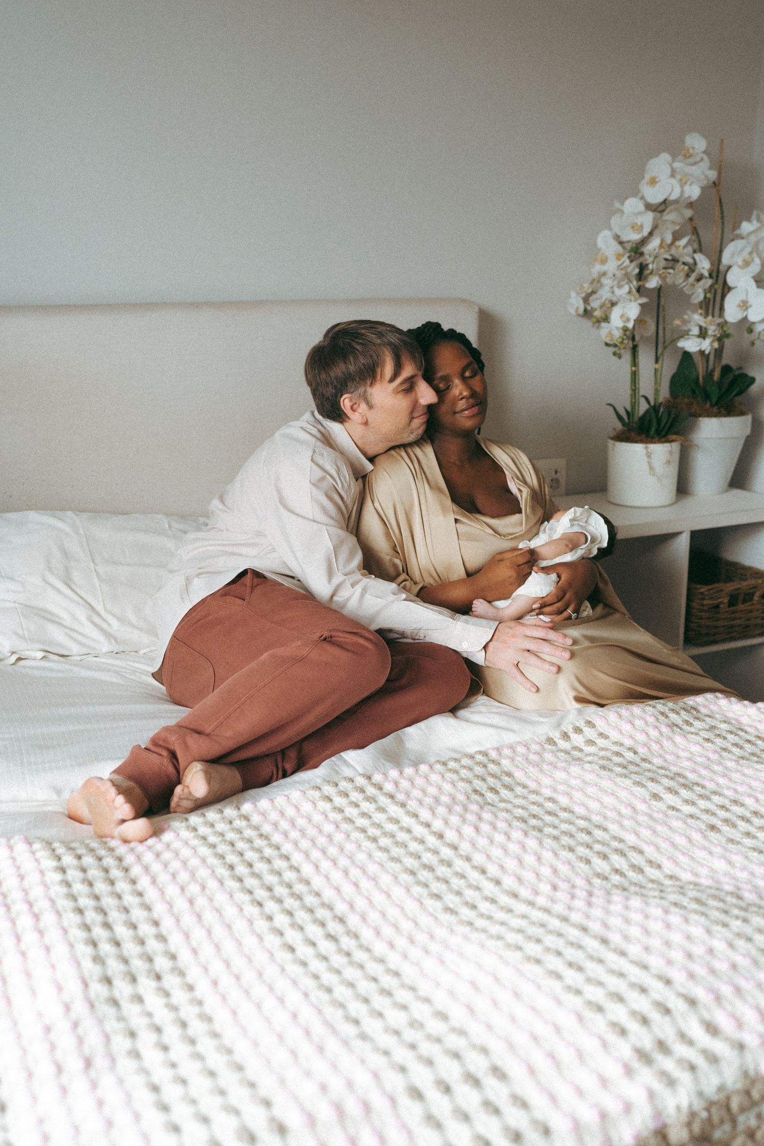 Intimate moment captured on white textured bedding with orchids decorating the background.