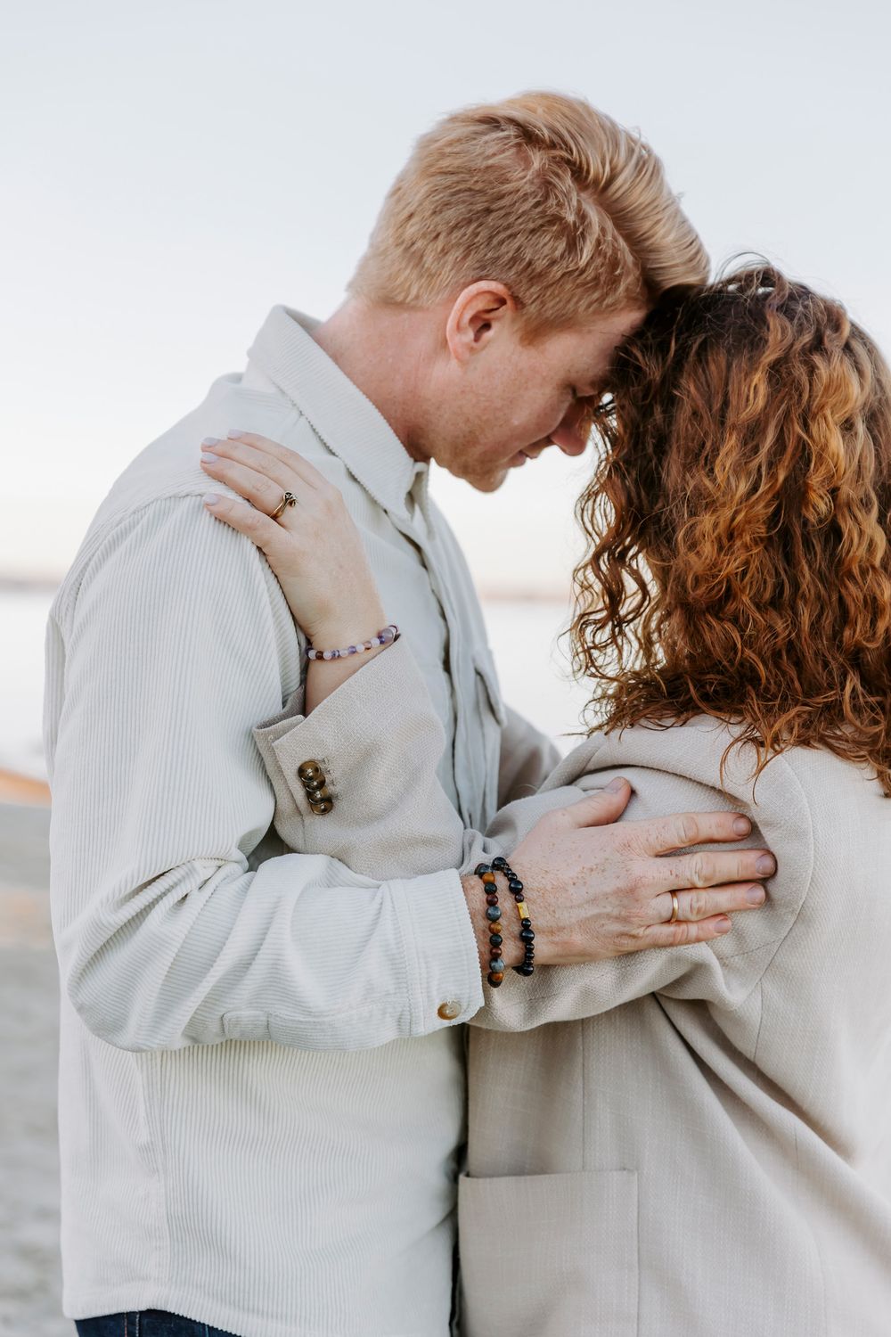 Romantisk omfavnelse fotograferet i blødt naturligt lys med koordinerede lyse outfits. Branding fotograf Fyn.