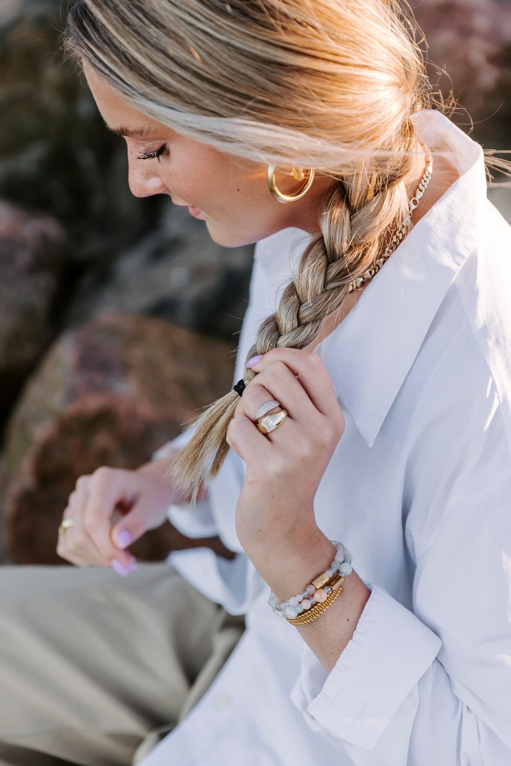 Person i hvid skjorte med knapper og flettet hår kigger nedad eftertænksomt. Branding fotograf Fyn.