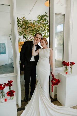 A series of romantic wedding photos showing a couple in formal attire posing together in a bright white room with red flowers.