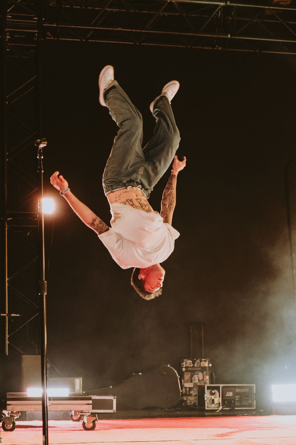 Performer executing an impressive aerial flip on stage with dramatic lighting.