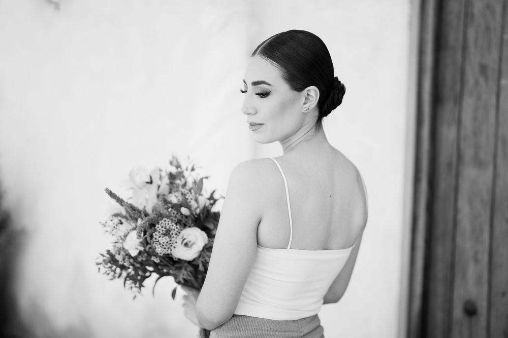Elegant bridal portrait with a flowing white gown and delicate bouquet in natural window light.