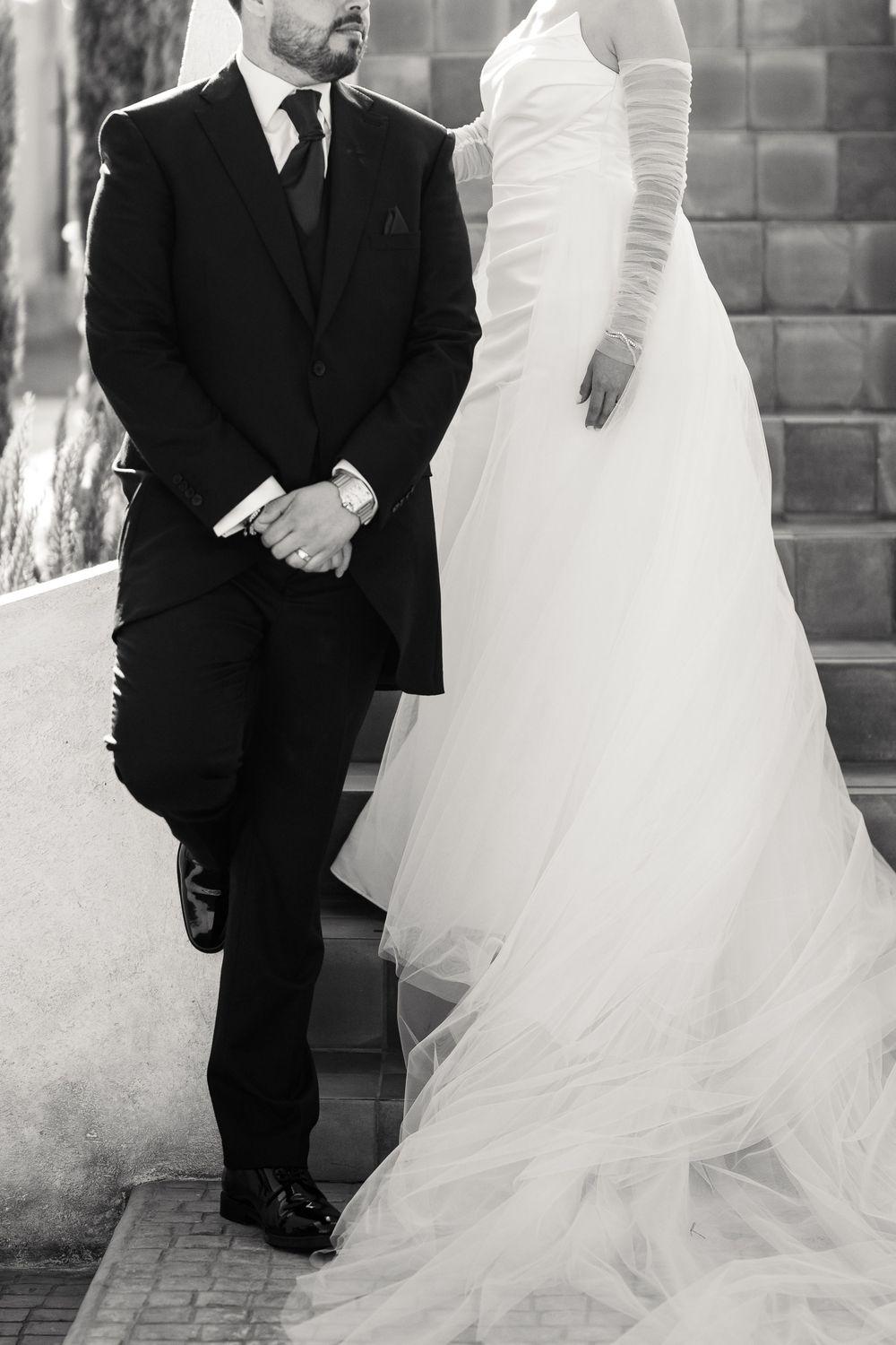 Black and white wedding portraits showing contrast between formal suit and flowing bridal gown.