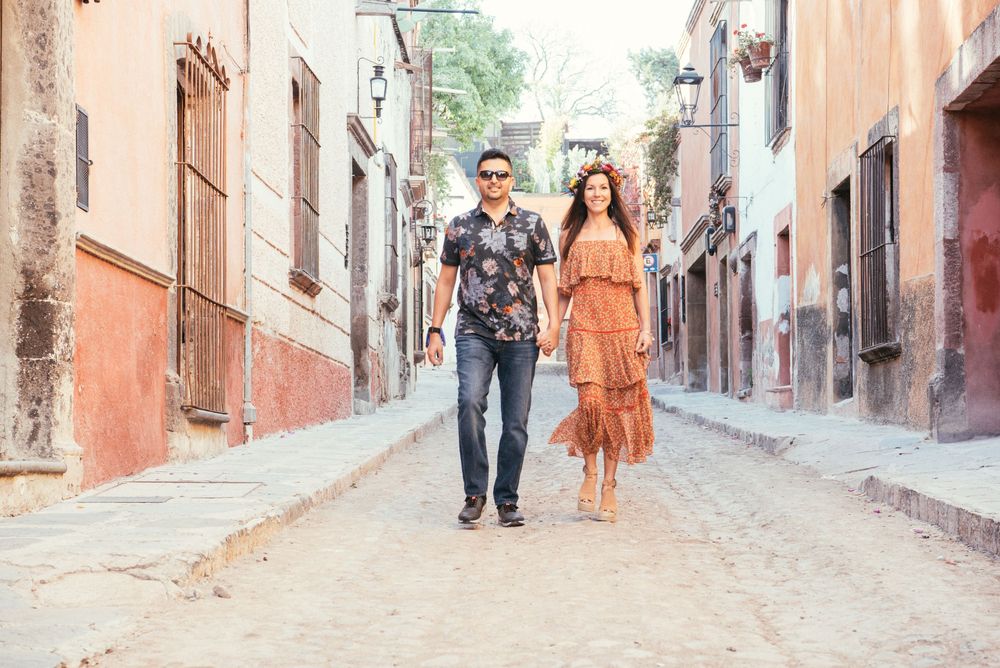 People walking through narrow cobblestone streets between colorful colonial buildings in San Miguel de Allende, Mexico.