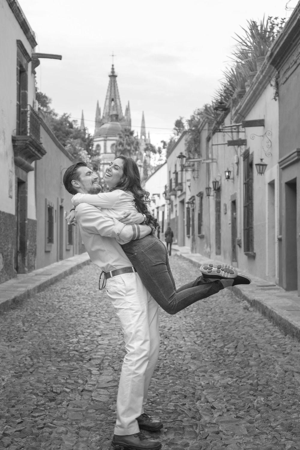 A sequence of black and white photos showing two dancers performing a dramatic dip on a cobblestone street.