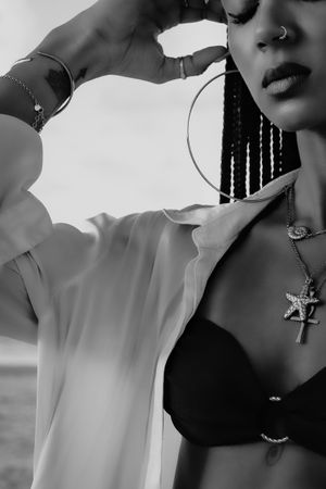 Artistic black and white portrait showing jewelry and fashion details in dramatic lighting.