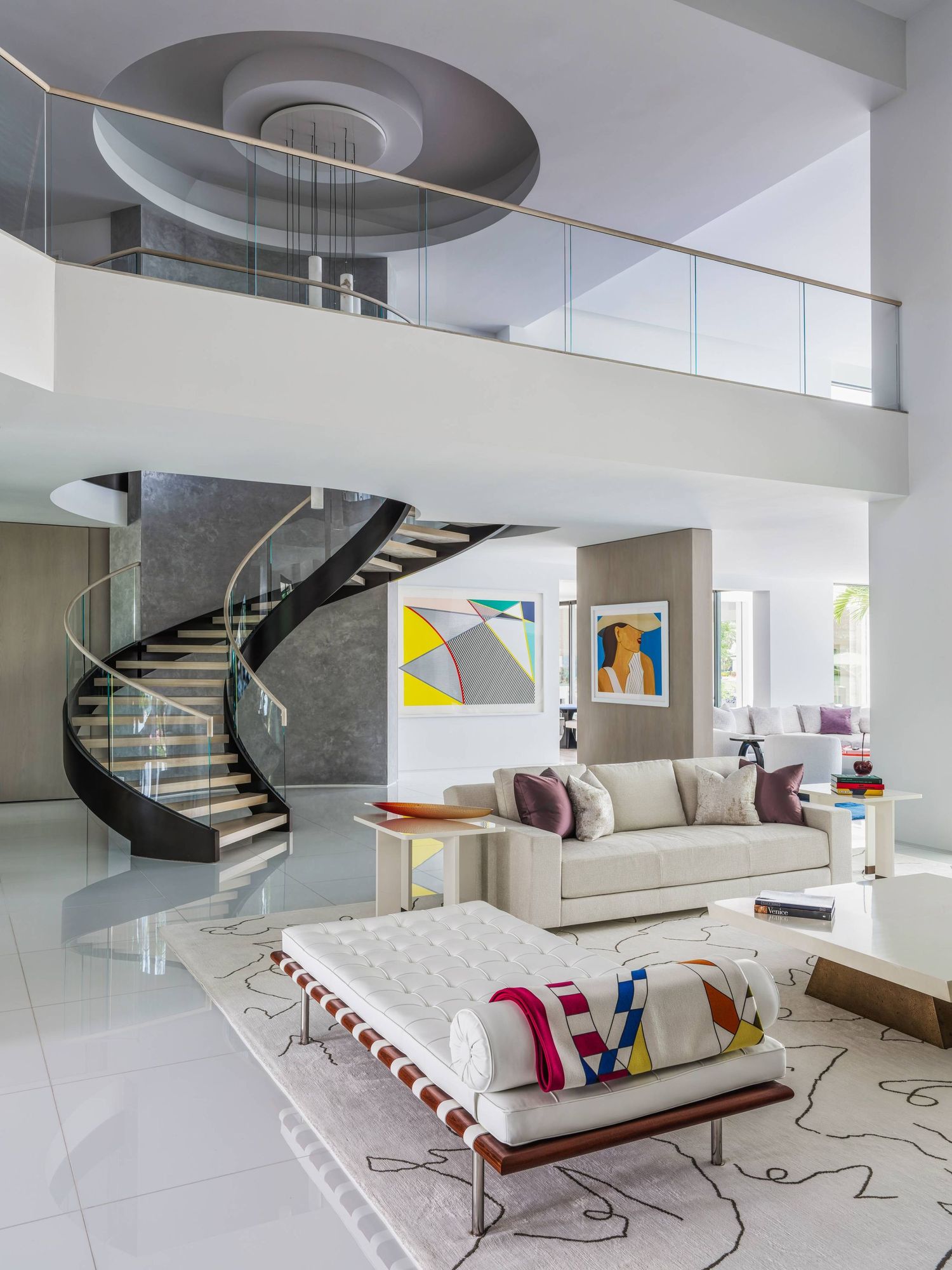 Double-height living room with dramatic spiral staircase and modern white furnishings.