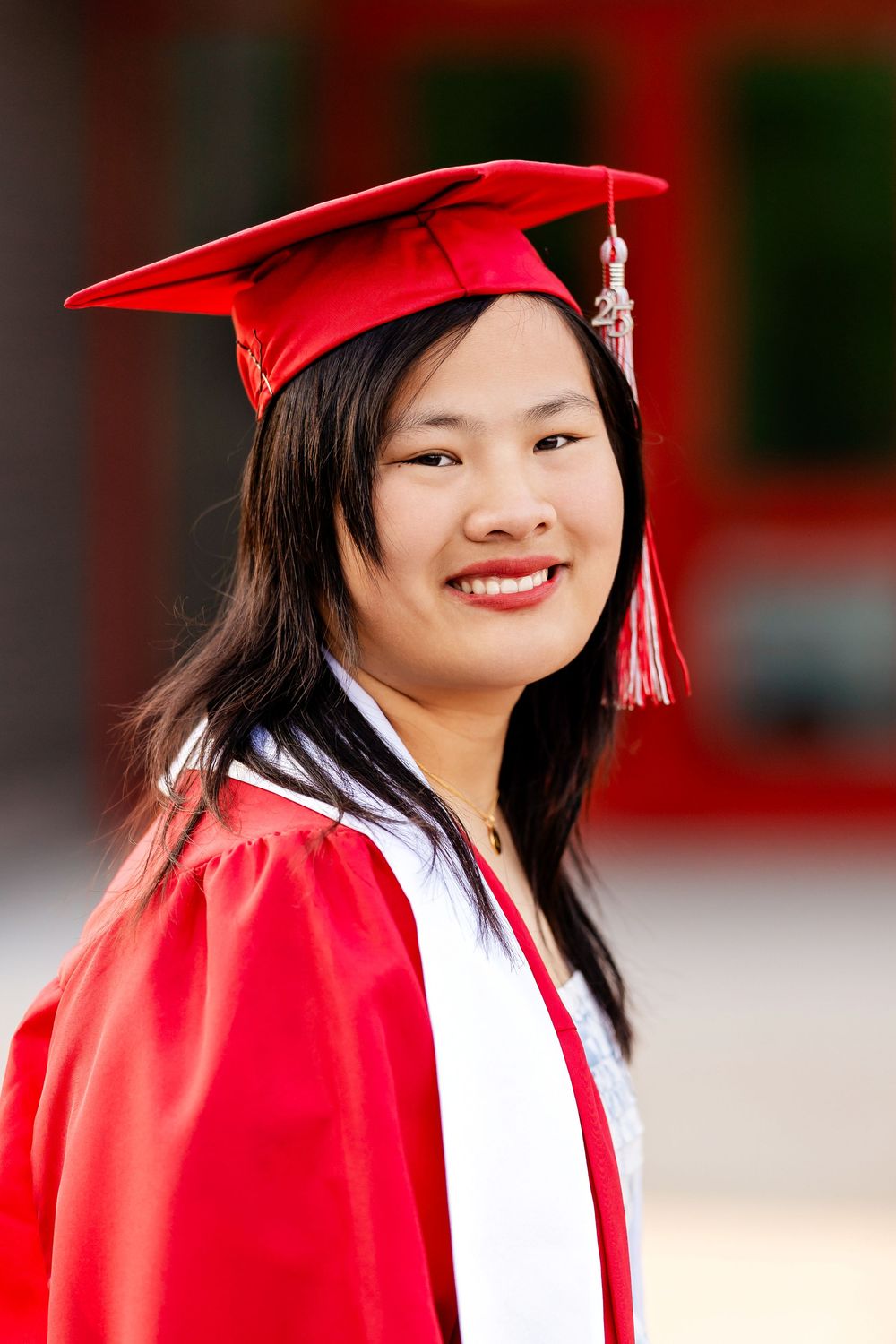 A graduate in regalia looking at the camera in front of a school taken by Milwaukee senior photographer Rachel Dickman.