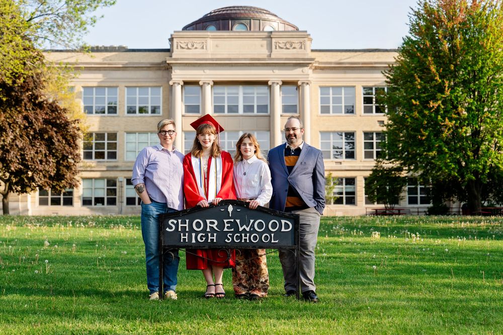 A family and graduate in front of a lawn sign at a school taken by Milwaukee senior photographer Rachel Dickman.