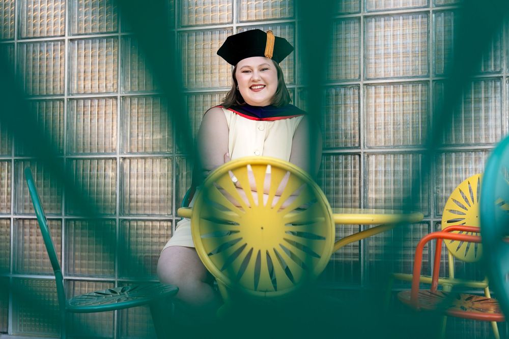 A graduate wearing her cap and stole sitting at a table in an iconic location taken by Milwaukee senior photographer Rachel Dickman.