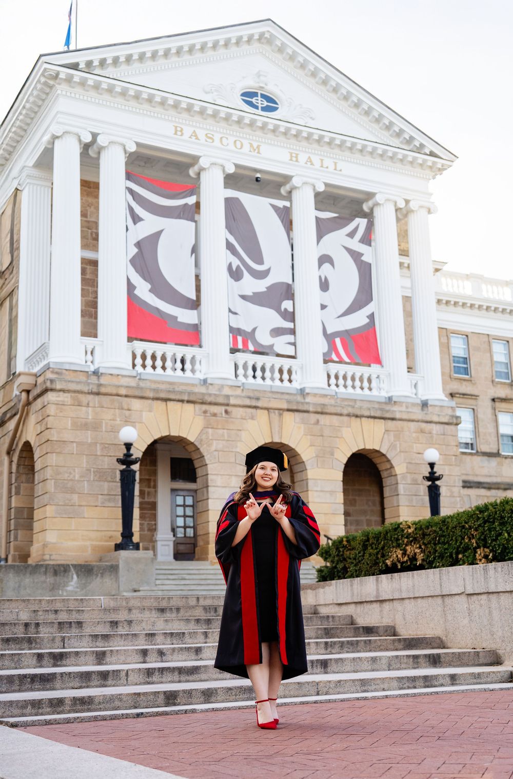 A graduate wearing full regalia in front of an iconic building taken by Milwaukee photographer Rachel Dickman.
