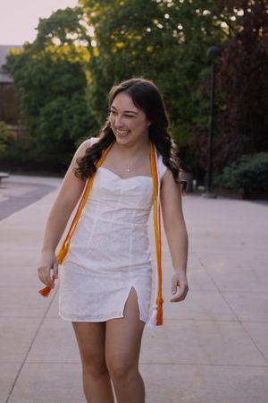 A woman walking and laughing outside on campus for graduation day