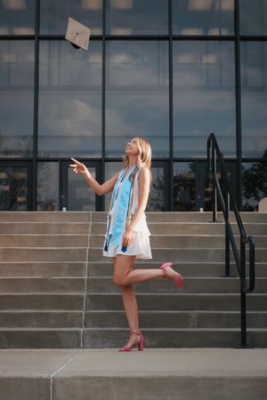 Young woman on graduation tossing her graduation cap into the air and smiling