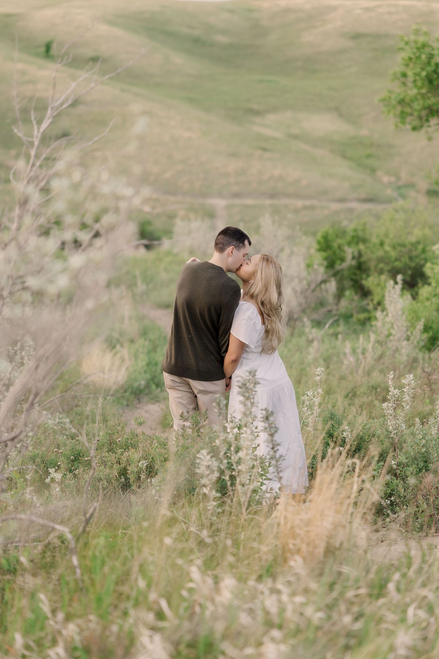A romantic couple shares an intimate moment in a blooming sunflower field at sunset.