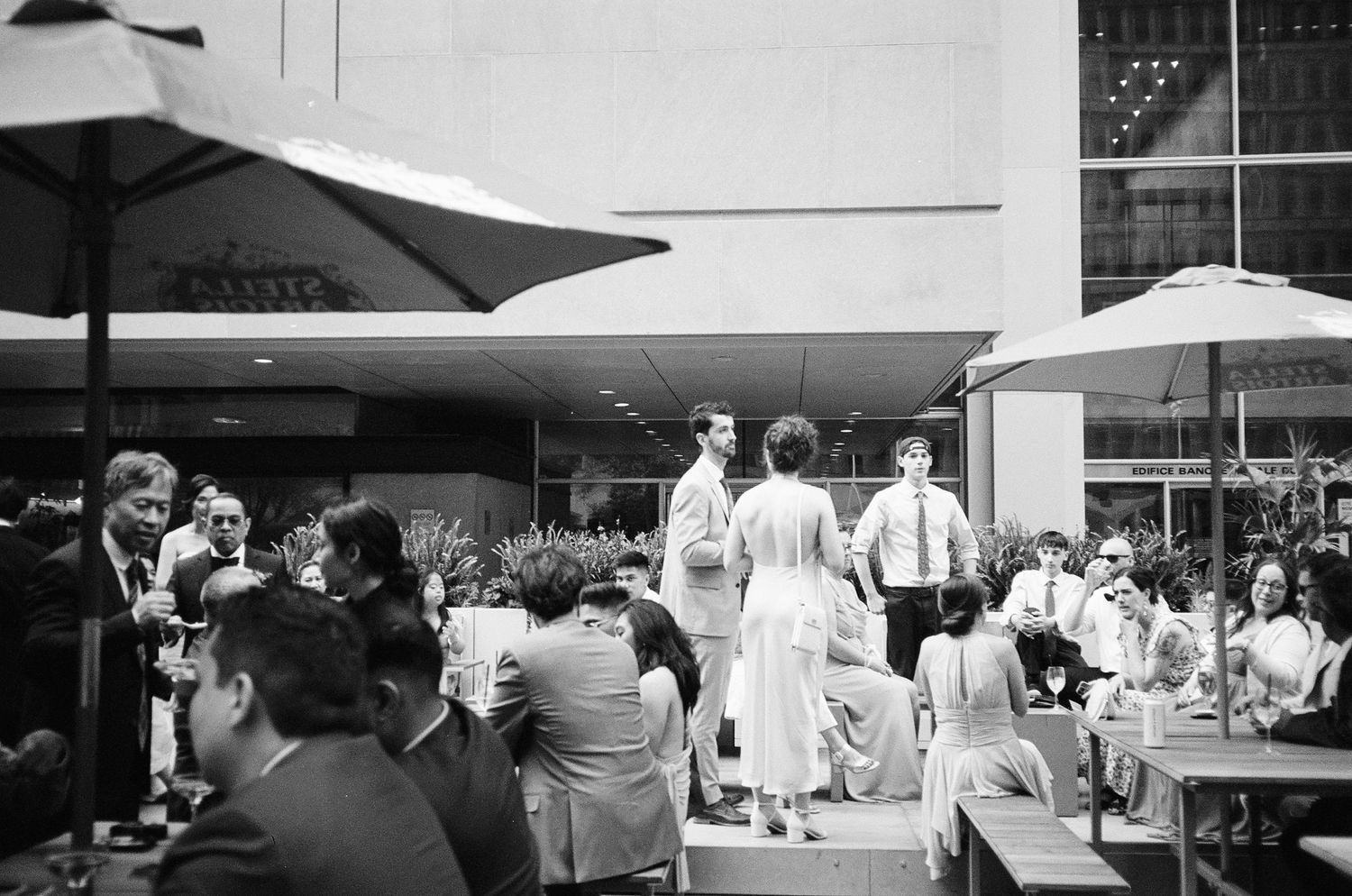 Restaurant guests dine under white umbrellas on an outdoor patio during a sunny day.