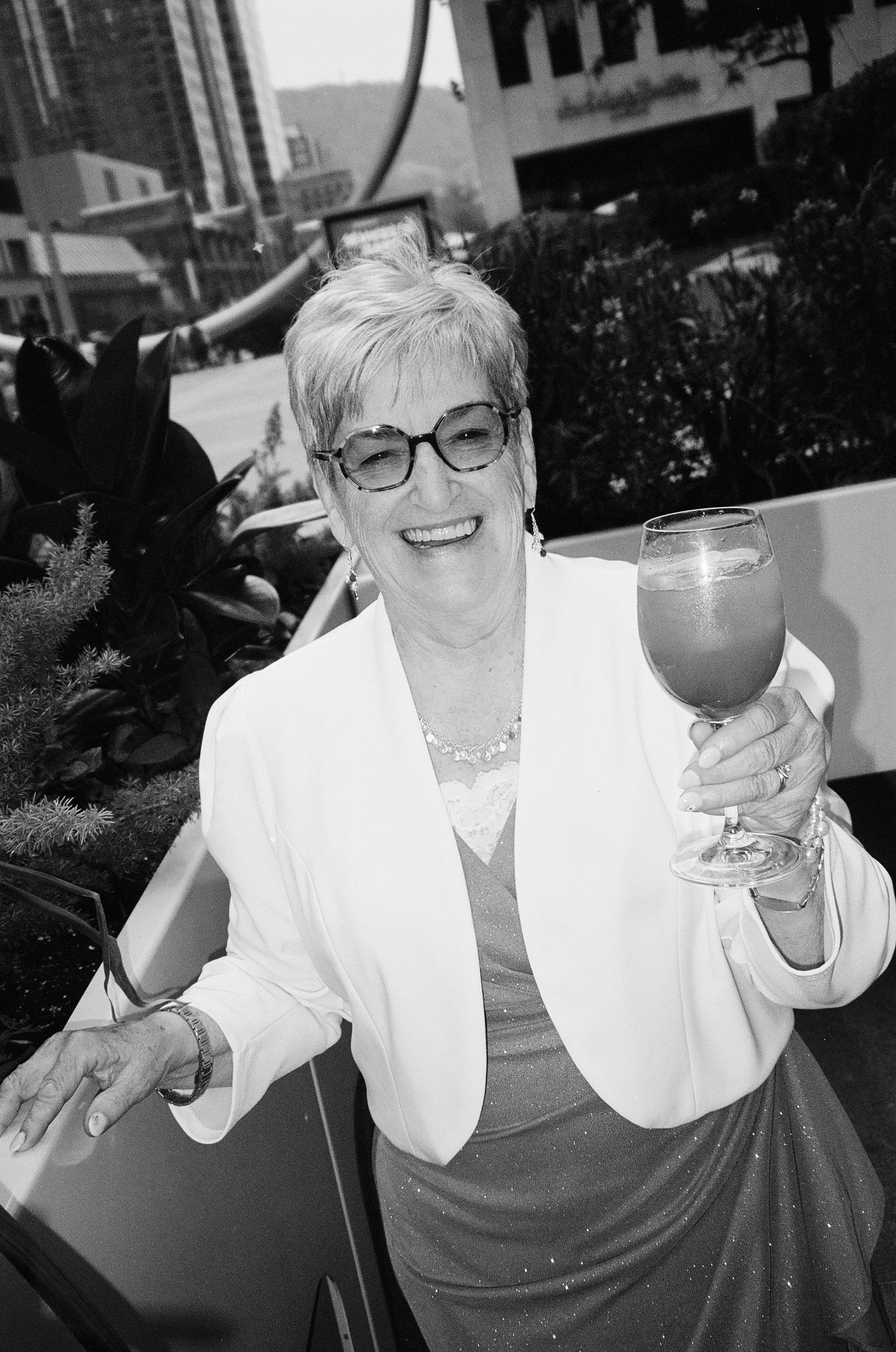 Series of black and white photos showing someone in glasses and white top enjoying drinks outdoors.