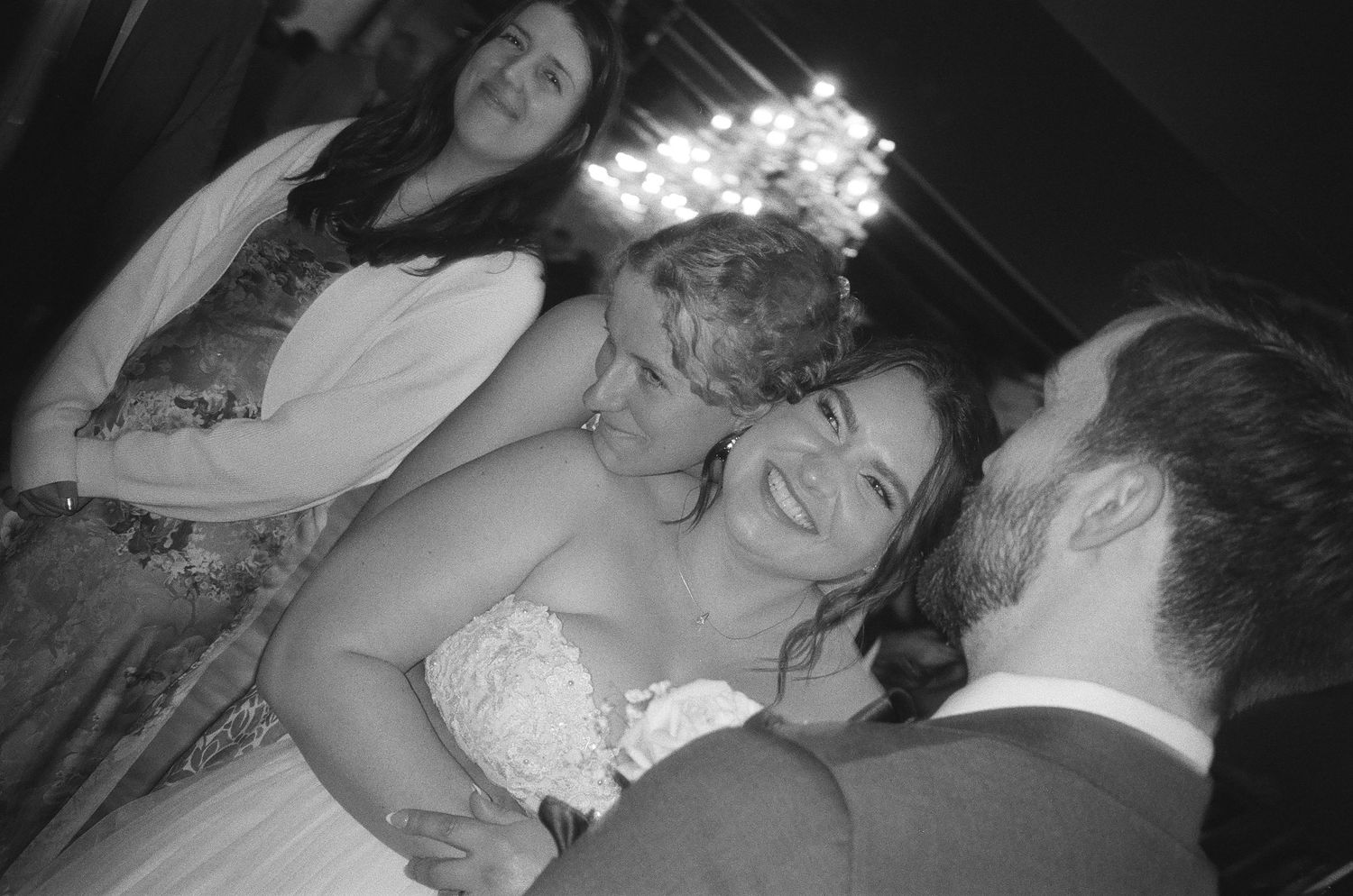A black and white photo montage showing candid moments from a wedding celebration with dancing and embracing.