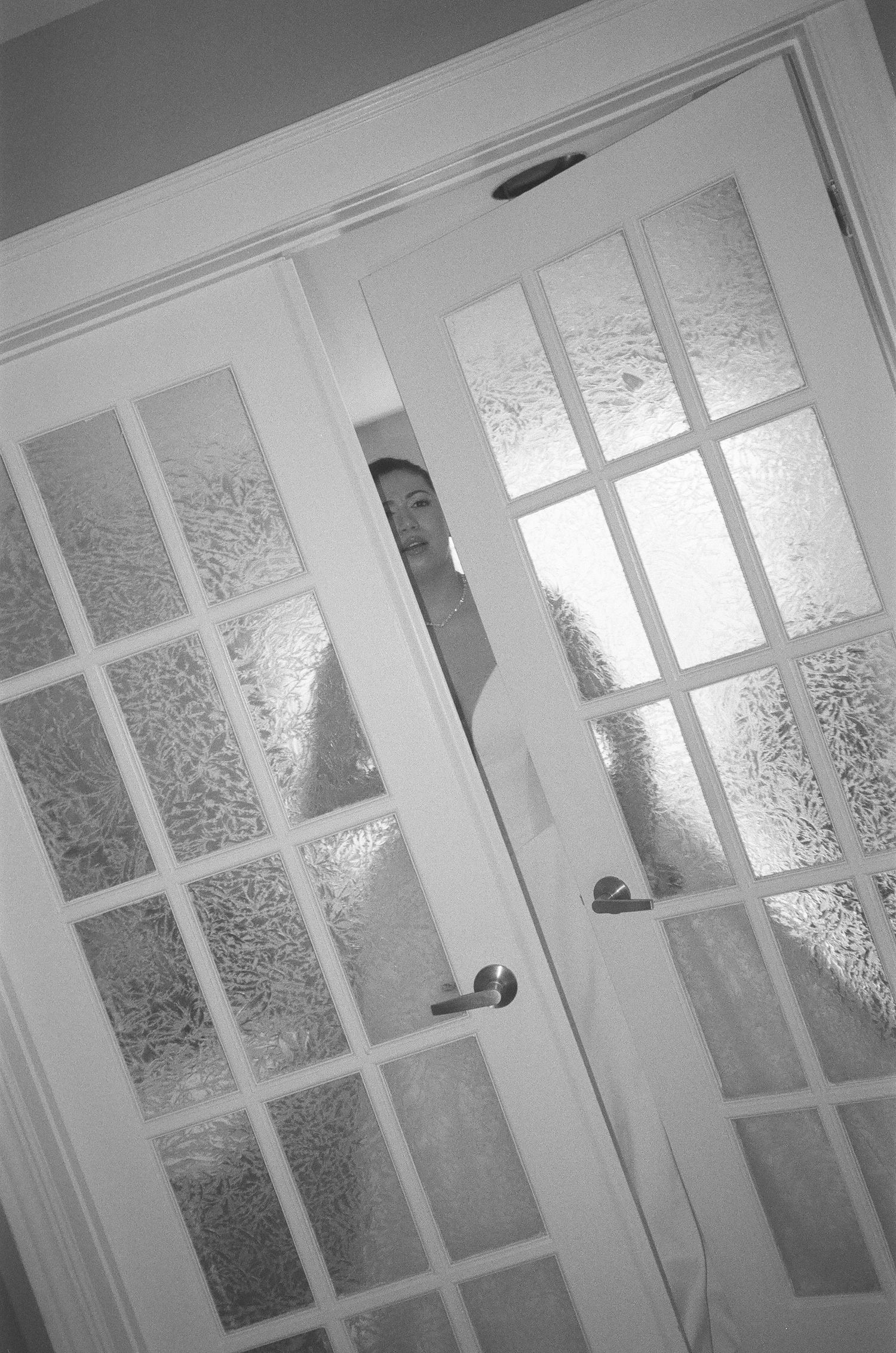Black and white sequence of a figure seen through frosted glass panels in an interior setting.