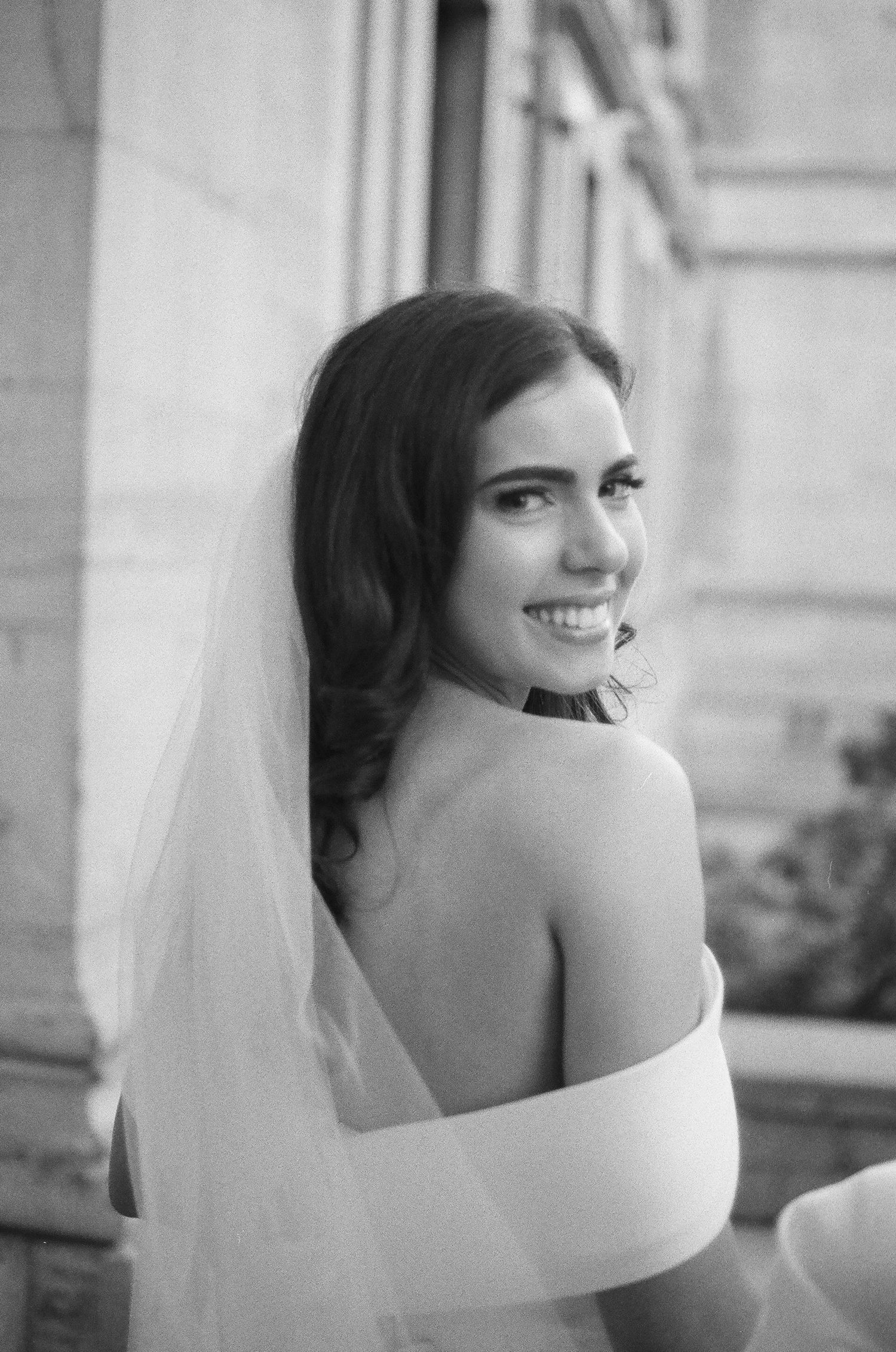 A series of black and white portraits showing a joyful bride in an off-shoulder wedding dress turning and smiling.