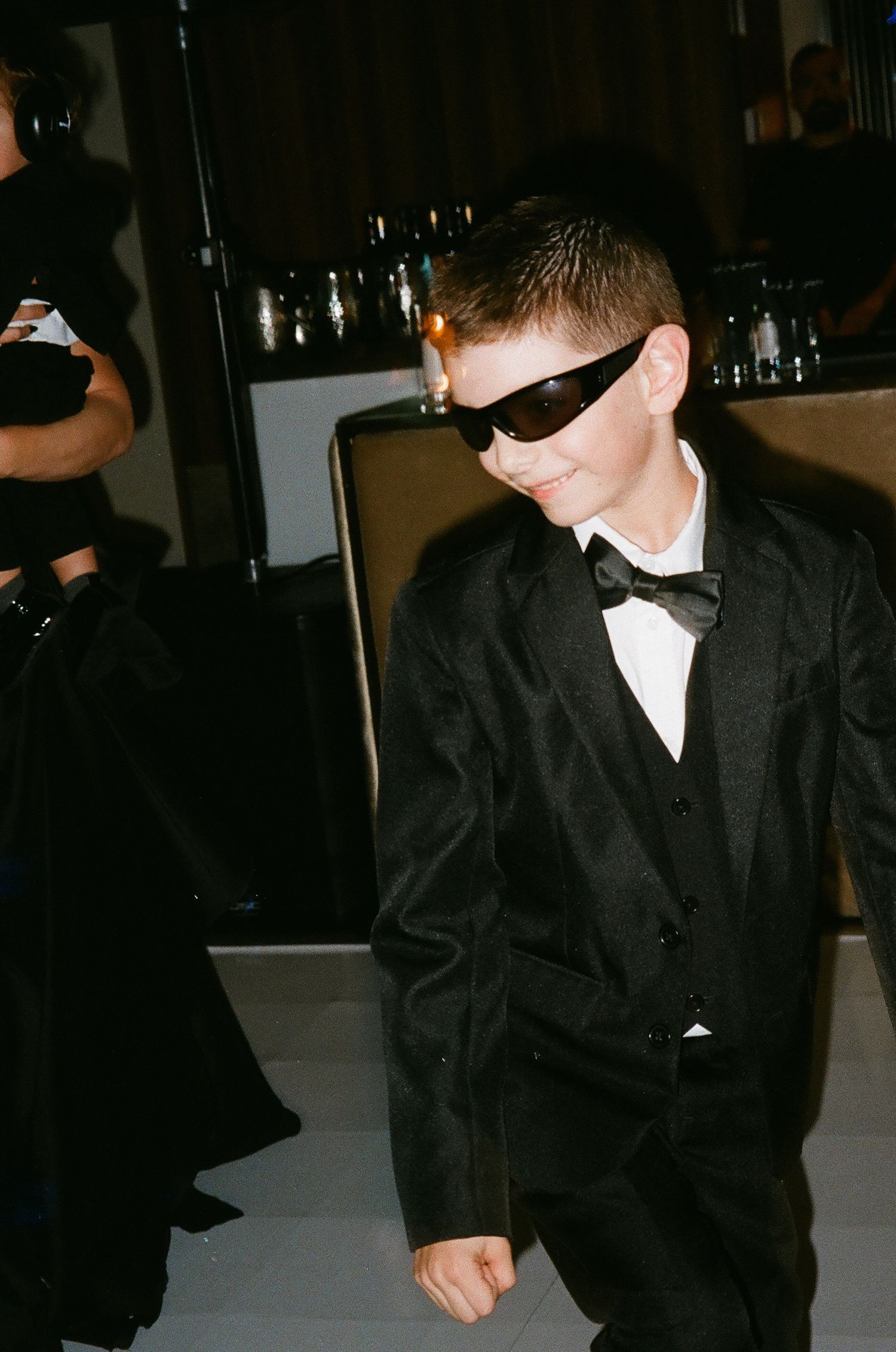 A person in formal black attire and bow tie at a dimly lit event or venue.