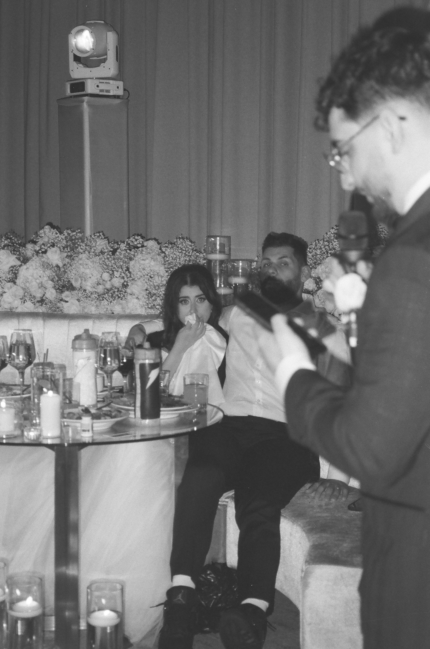 A black and white photo sequence showing people at a wedding reception indoors with decorative garlands.