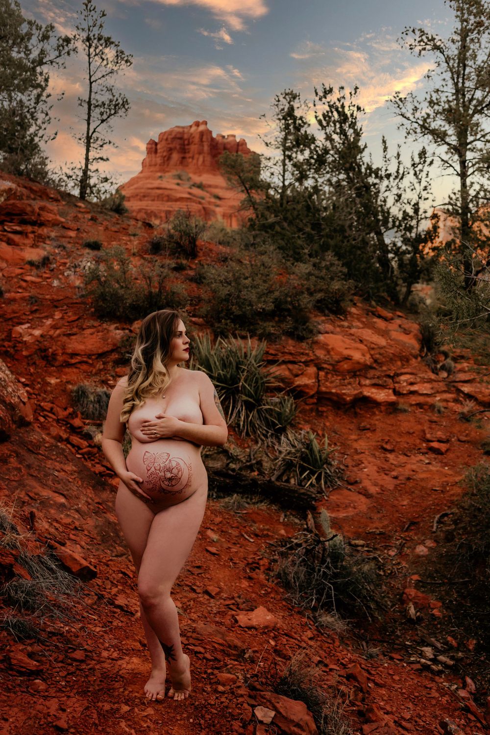 Sunset maternity portrait against iconic red rock formations in desert landscape.