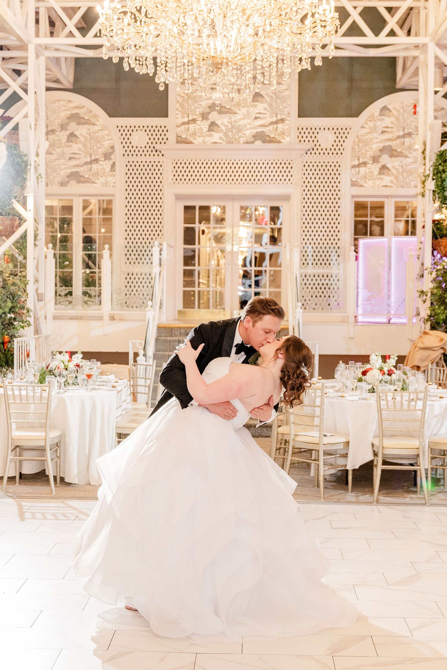 Elegant ballroom wedding reception venue with crystal chandelier and white decor.