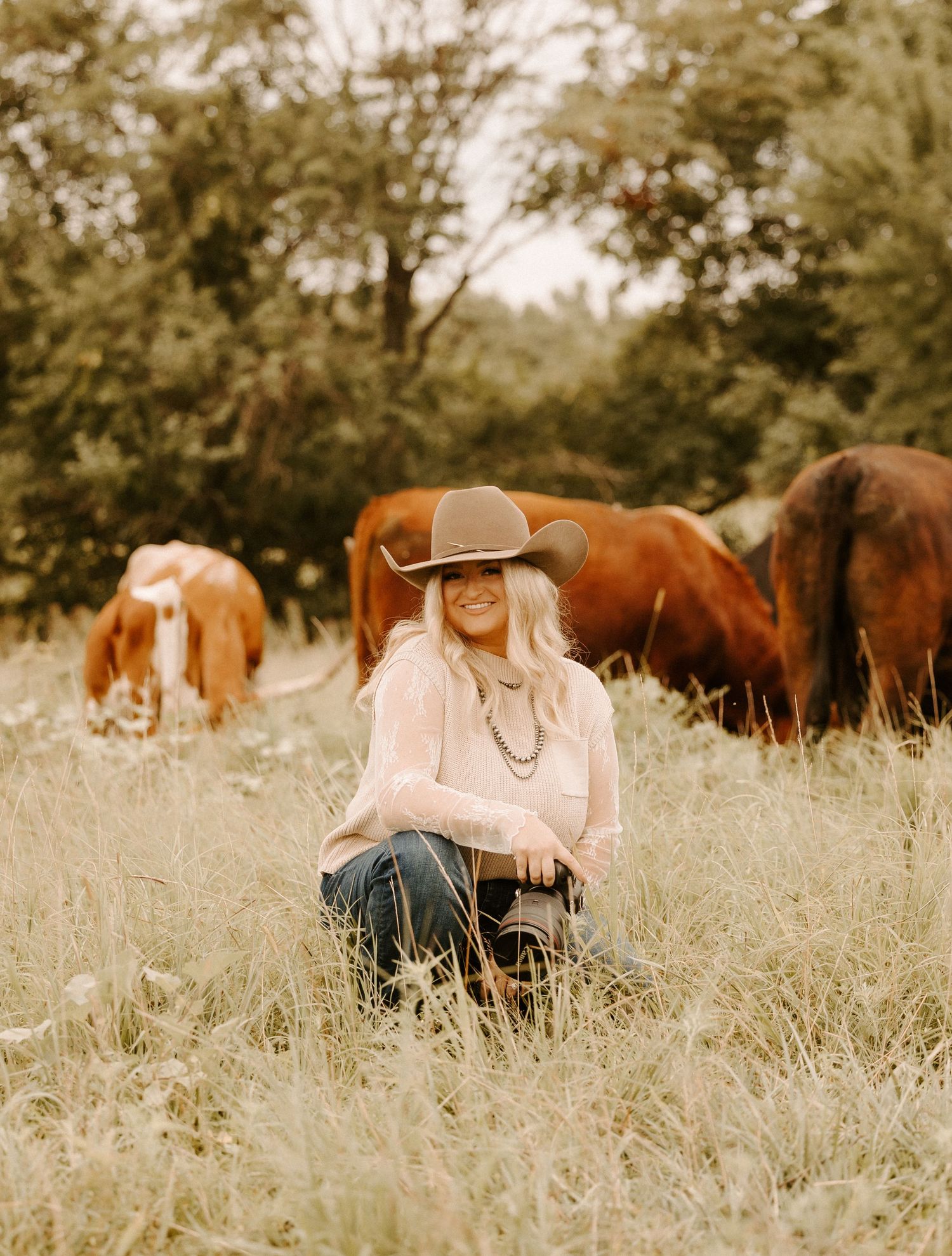 Brown horses graze peacefully in a sunlit field of tall grass at golden hour during self portraits in Gallatin, TN.