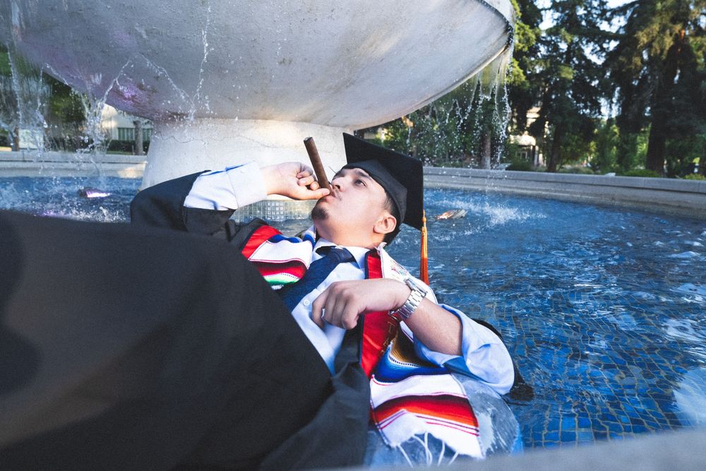 A person in red white and blue athletic wear splashes water from a fountain on a sunny day.