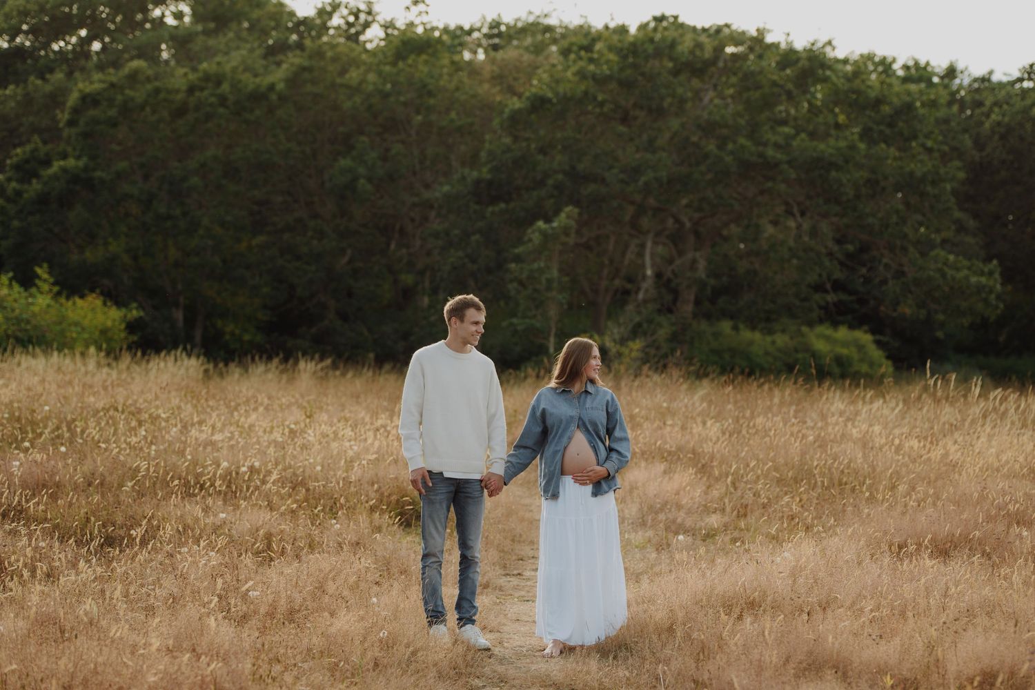 Expectant couple shares a tender moment in a wildflower meadow, cradling pregnant belly outdoors. Victoria, BC, Vancouver Island.