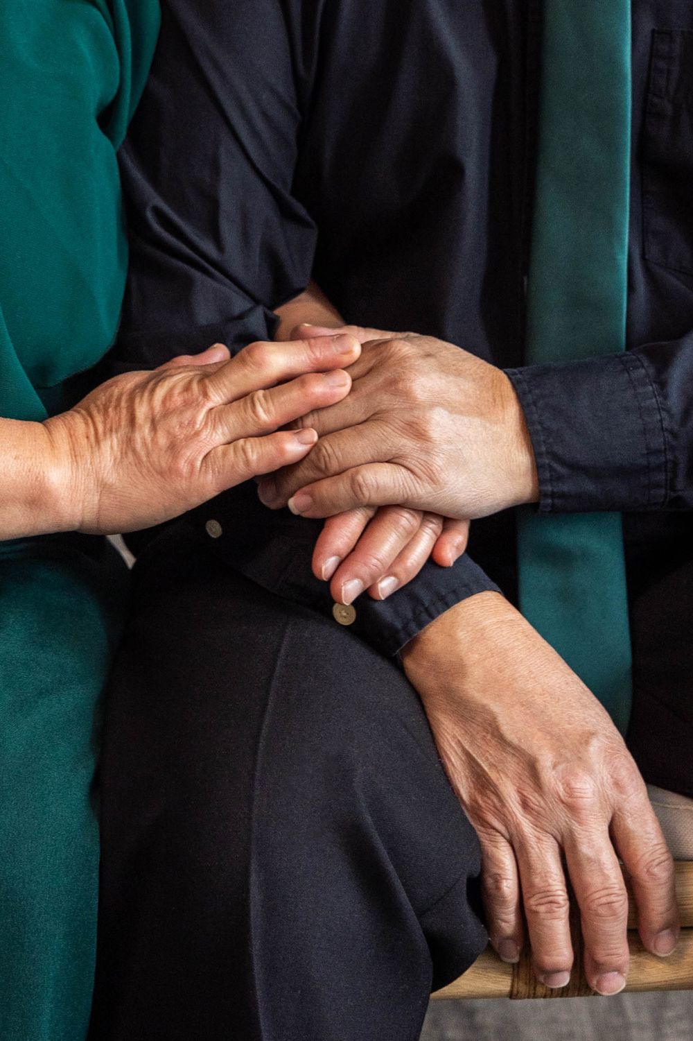Close-up sequence of hands gently touching and holding each other against a dark background.