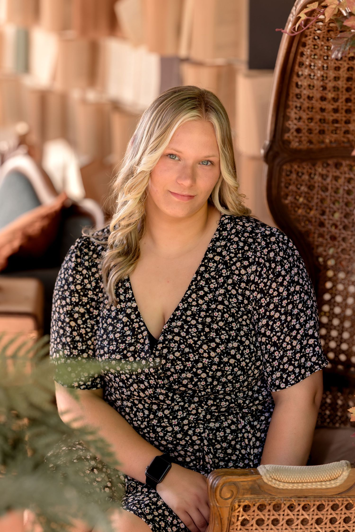 Indoor portrait session featuring floral print dress and wicker furniture.