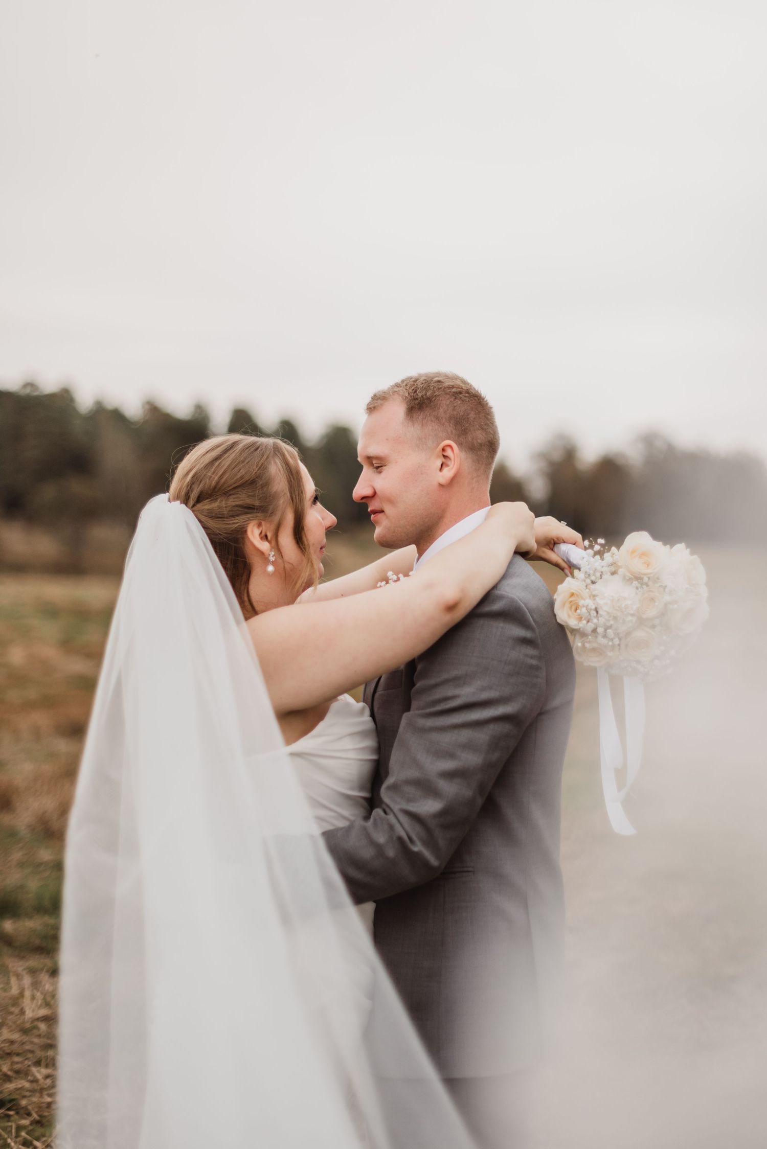 Romantic peach and coral rose wedding bouquet with delicate white wildflowers.