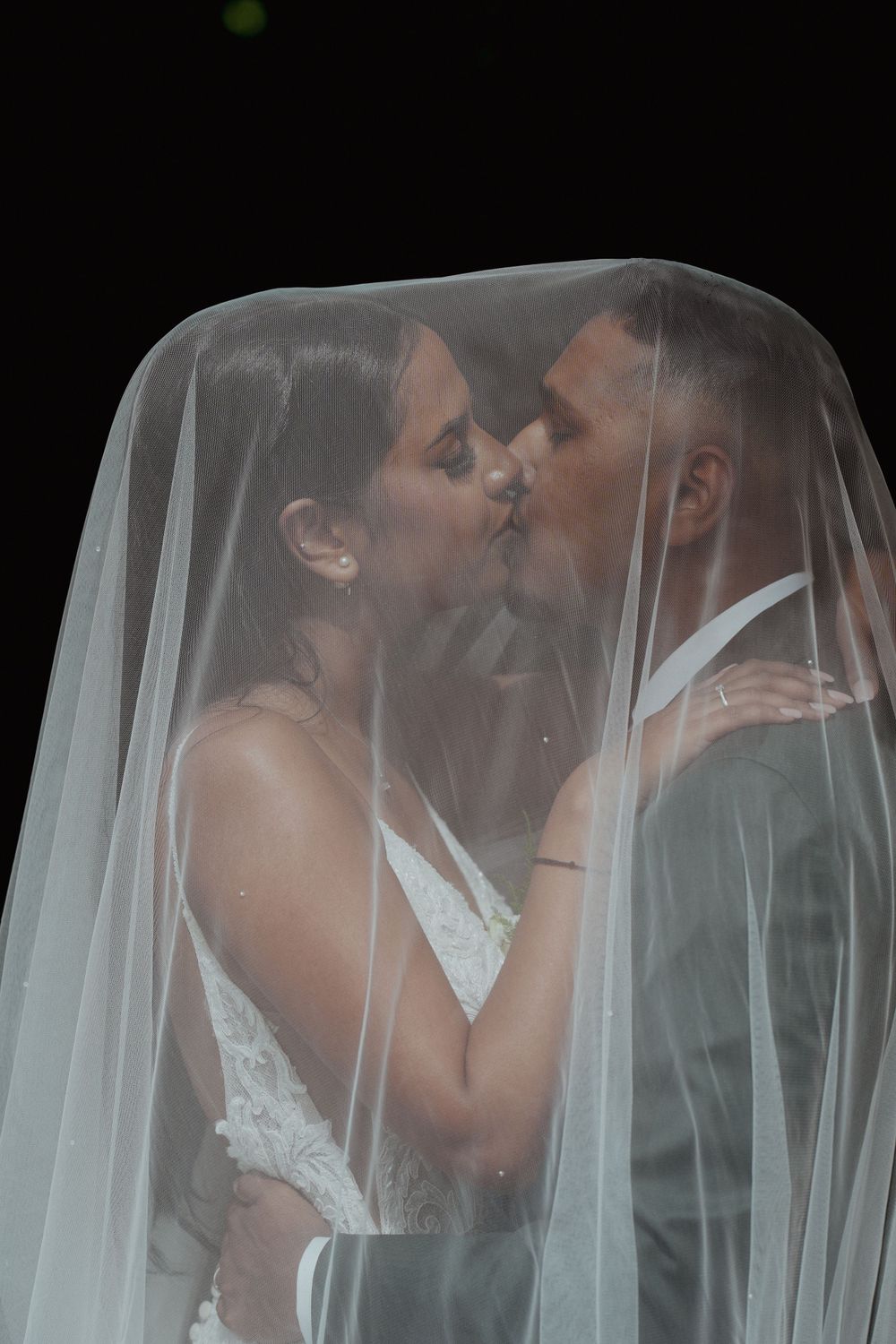 Romantic wedding portrait under flowing white veil.