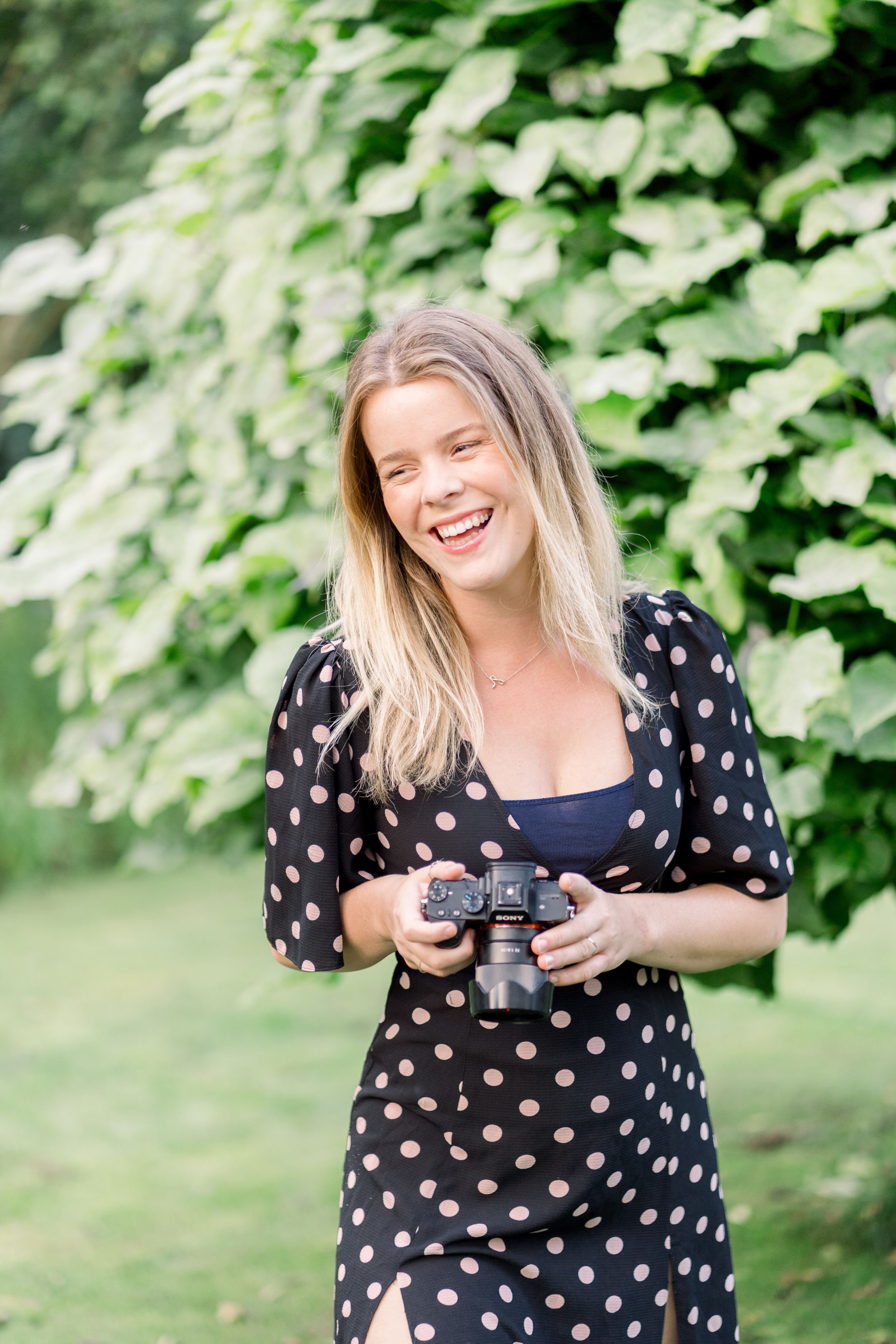 Photographer holding camera in her hand and smiling at Prestwold Hall