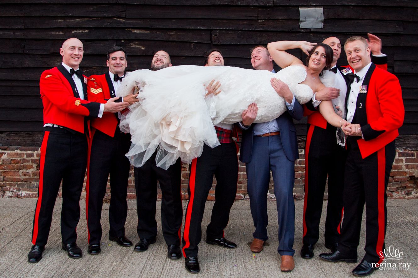 Bride carried by groom and best men all in army uniforms at Blackthorpe Barn near Bury St Edmunds